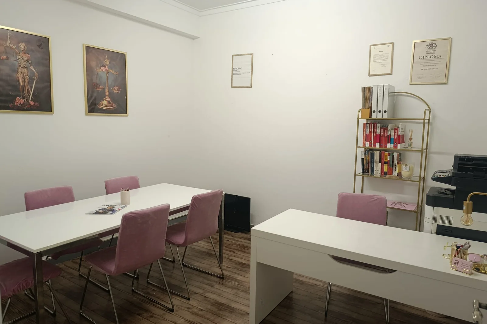 Escritório de atendimento com mesa de reuniões, quadros e estante